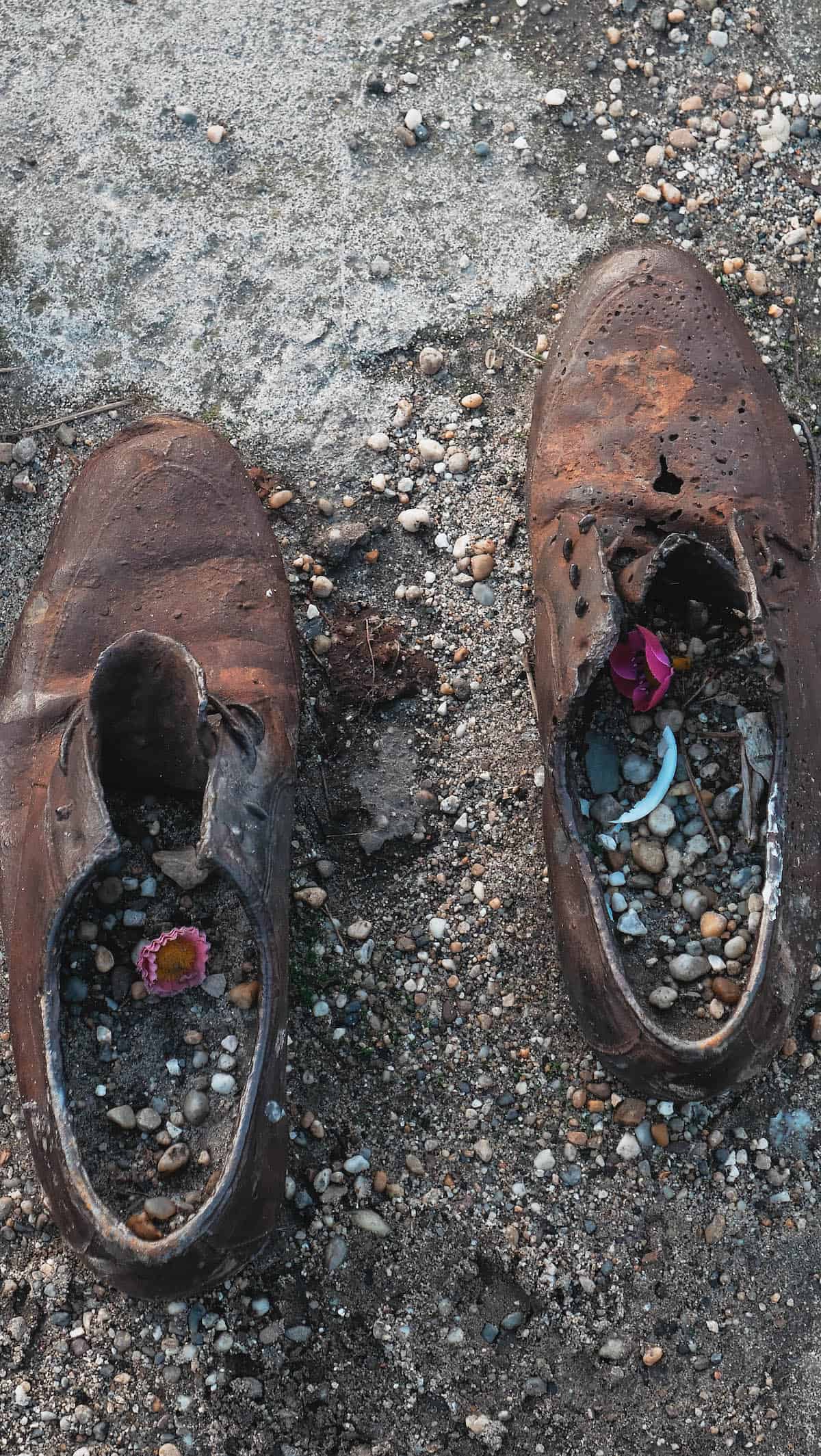 The Definitive Hungarian Goulash 21 A pair of antique shoes on the ground, serving as a poignant memorial next to the Danube River, a historic landmark of Budapest.