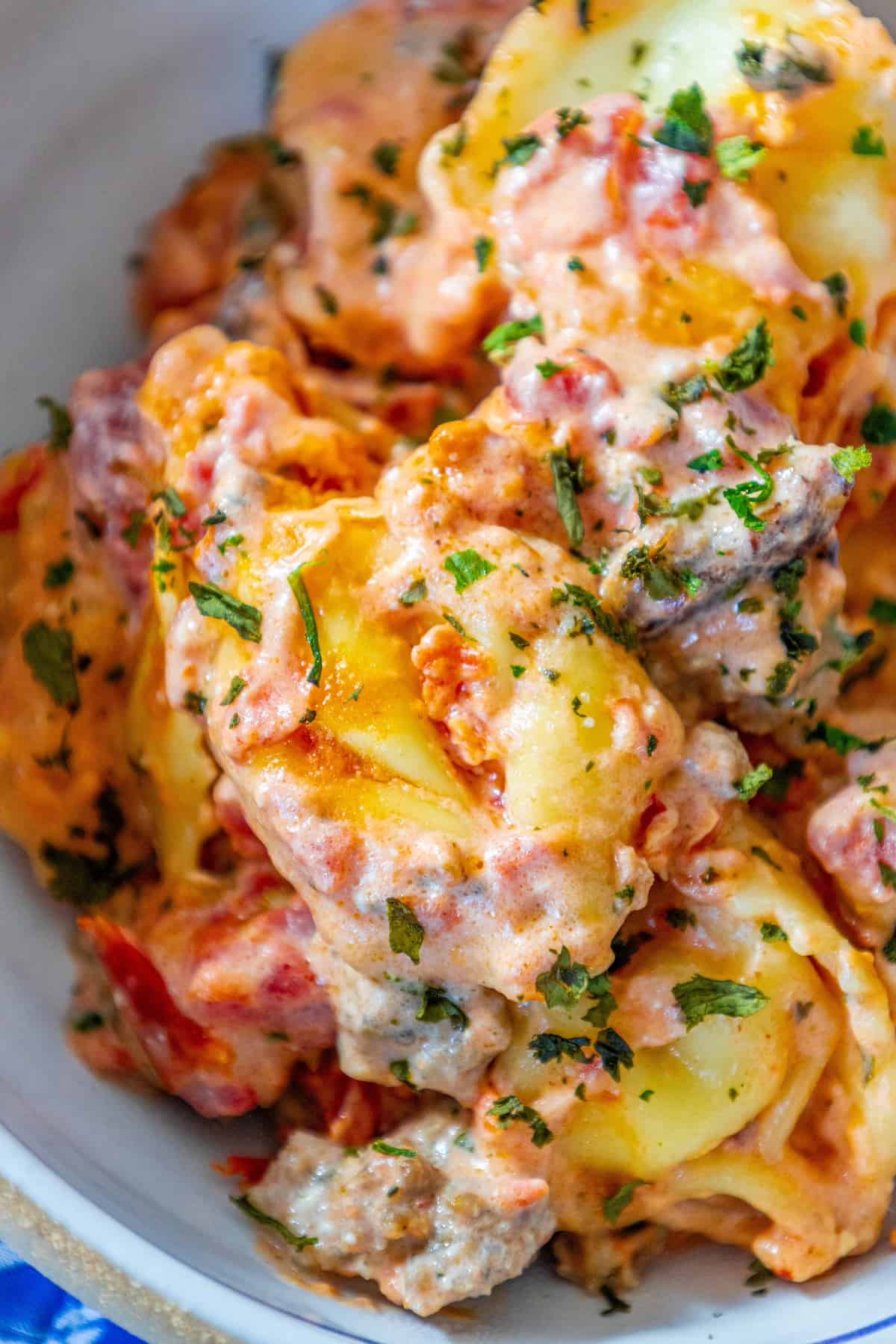 A cheesy bowl of potato salad with meat.