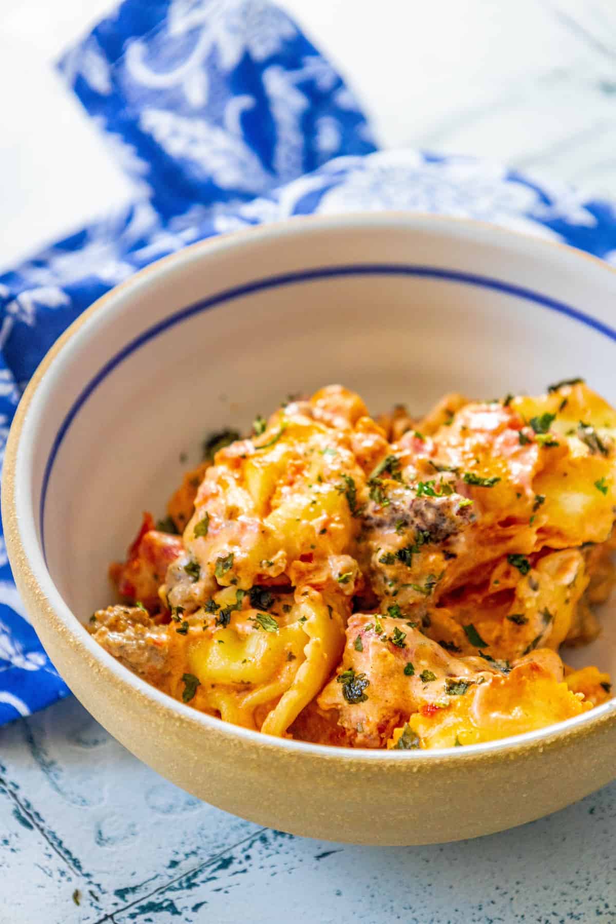 A cheesy bowl of baked tortellini with sauce.