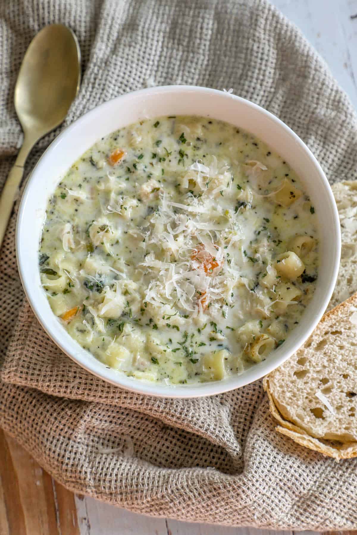 A creamy chicken noodle soup with bread on a table.