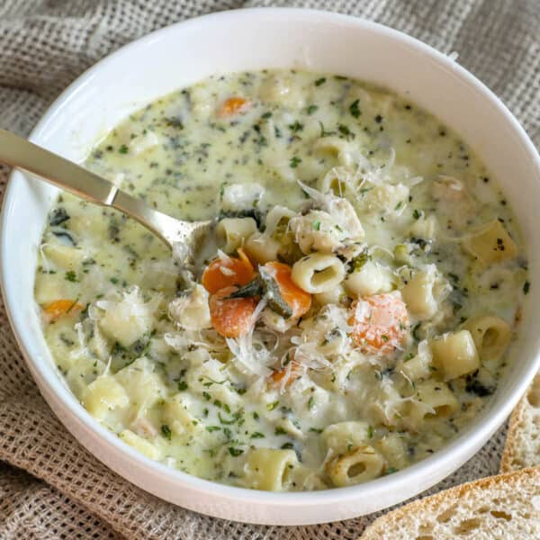 A creamy chicken noodle soup with bread on top.
