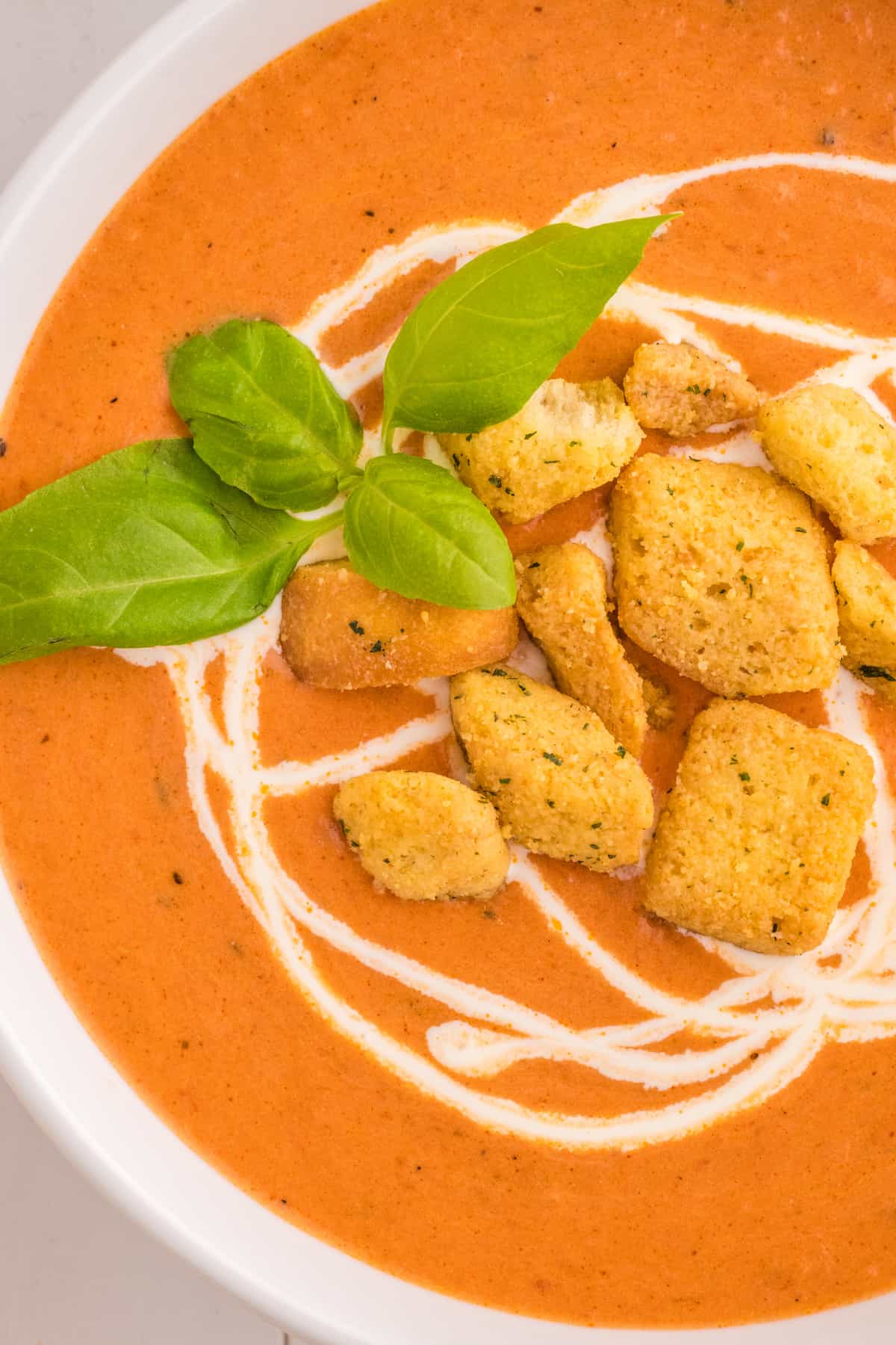 A creamy tomato soup with croutons and basil.
