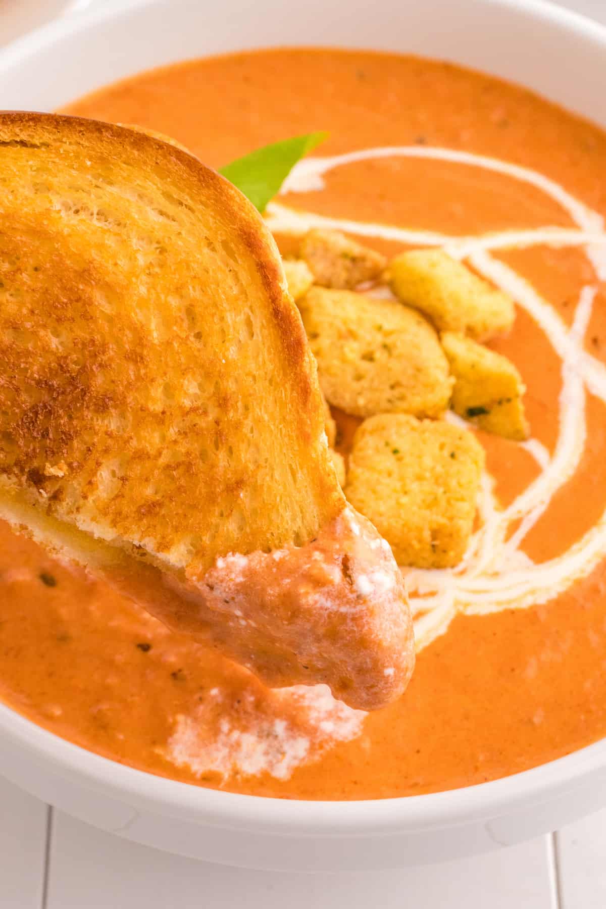 A creamy tomato soup with croutons in it.