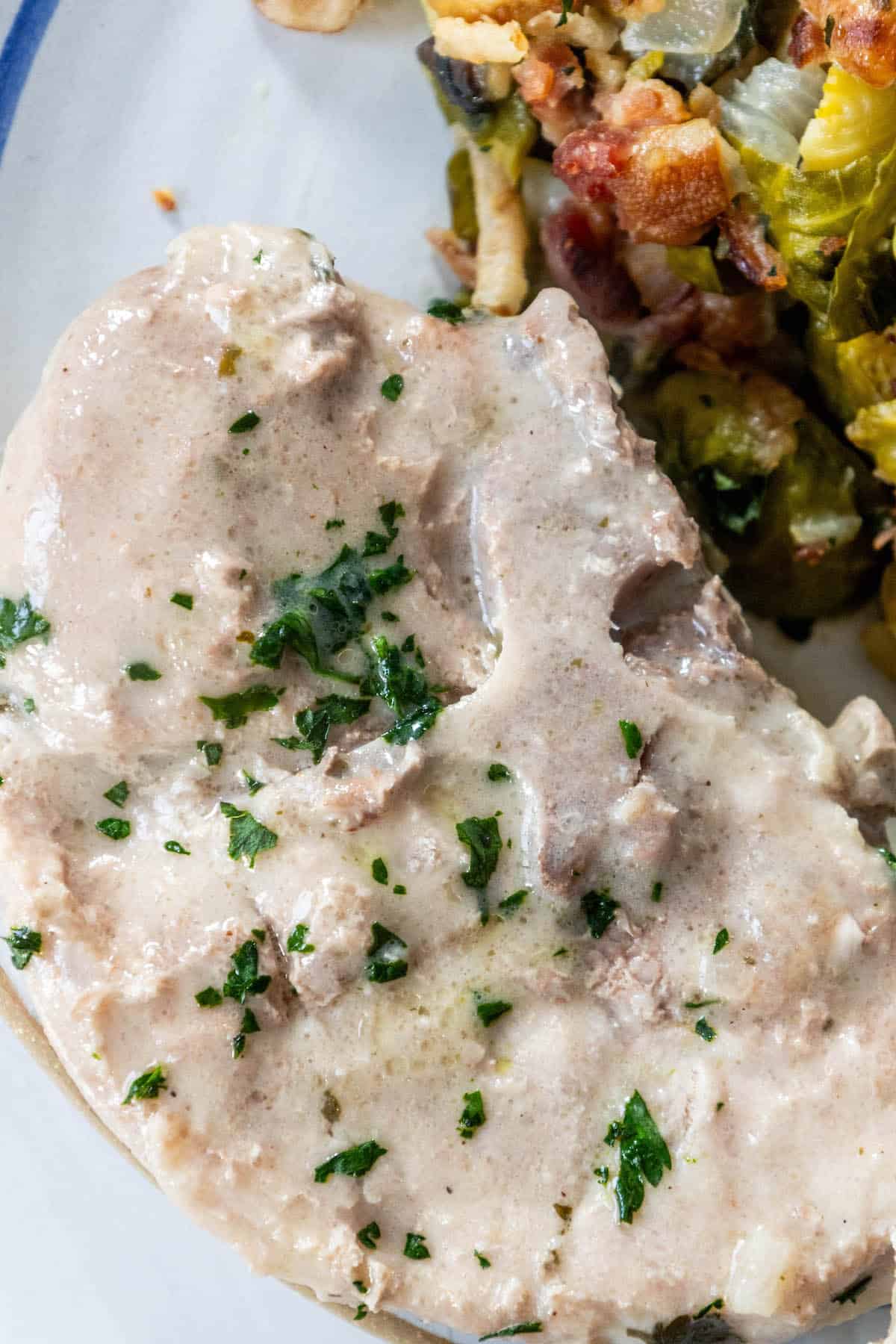 Creamy pork chops with gravy and brussels sprouts on a plate.