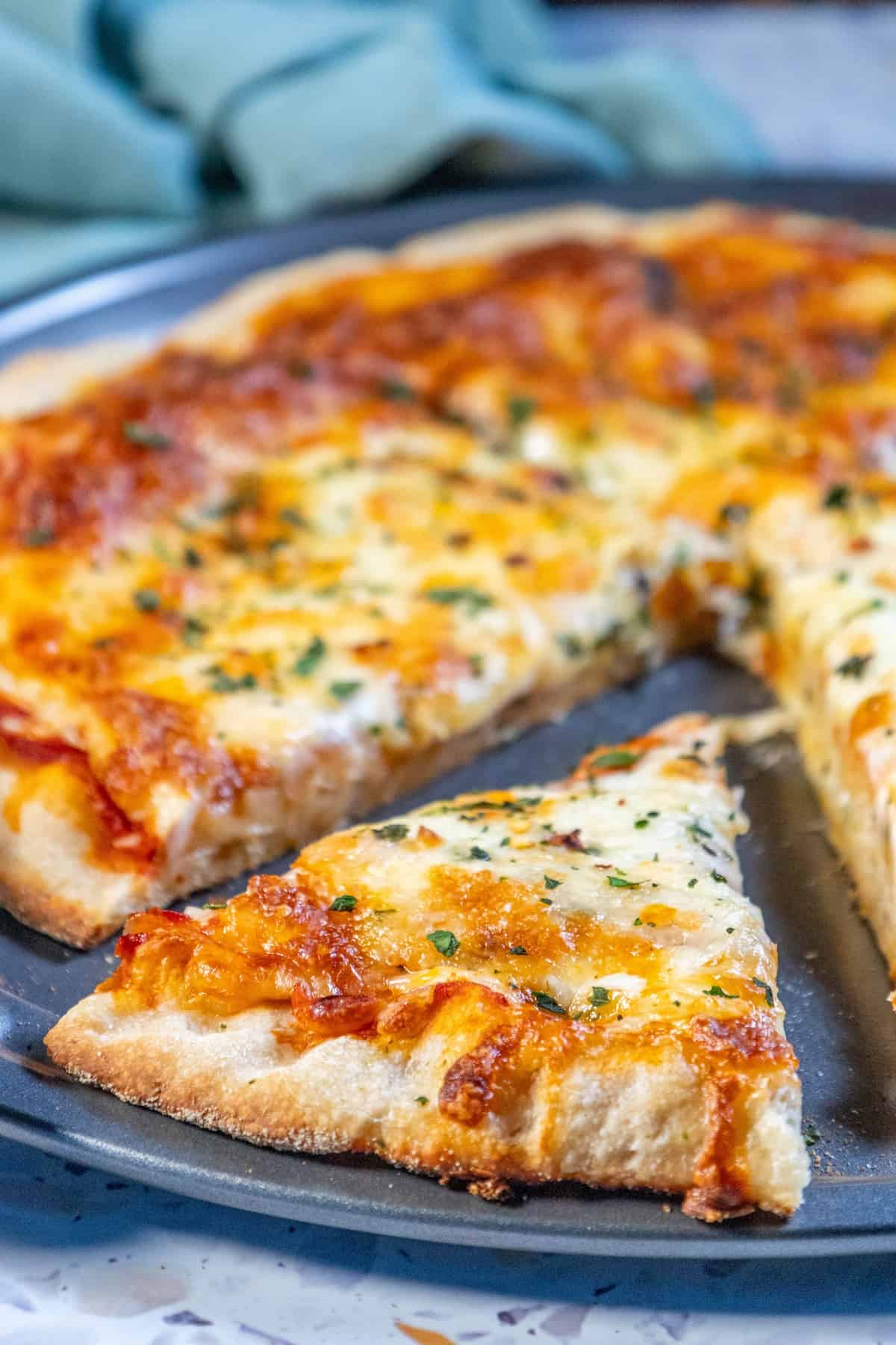 An easy homemade pizza with cheese and herbs on a plate.