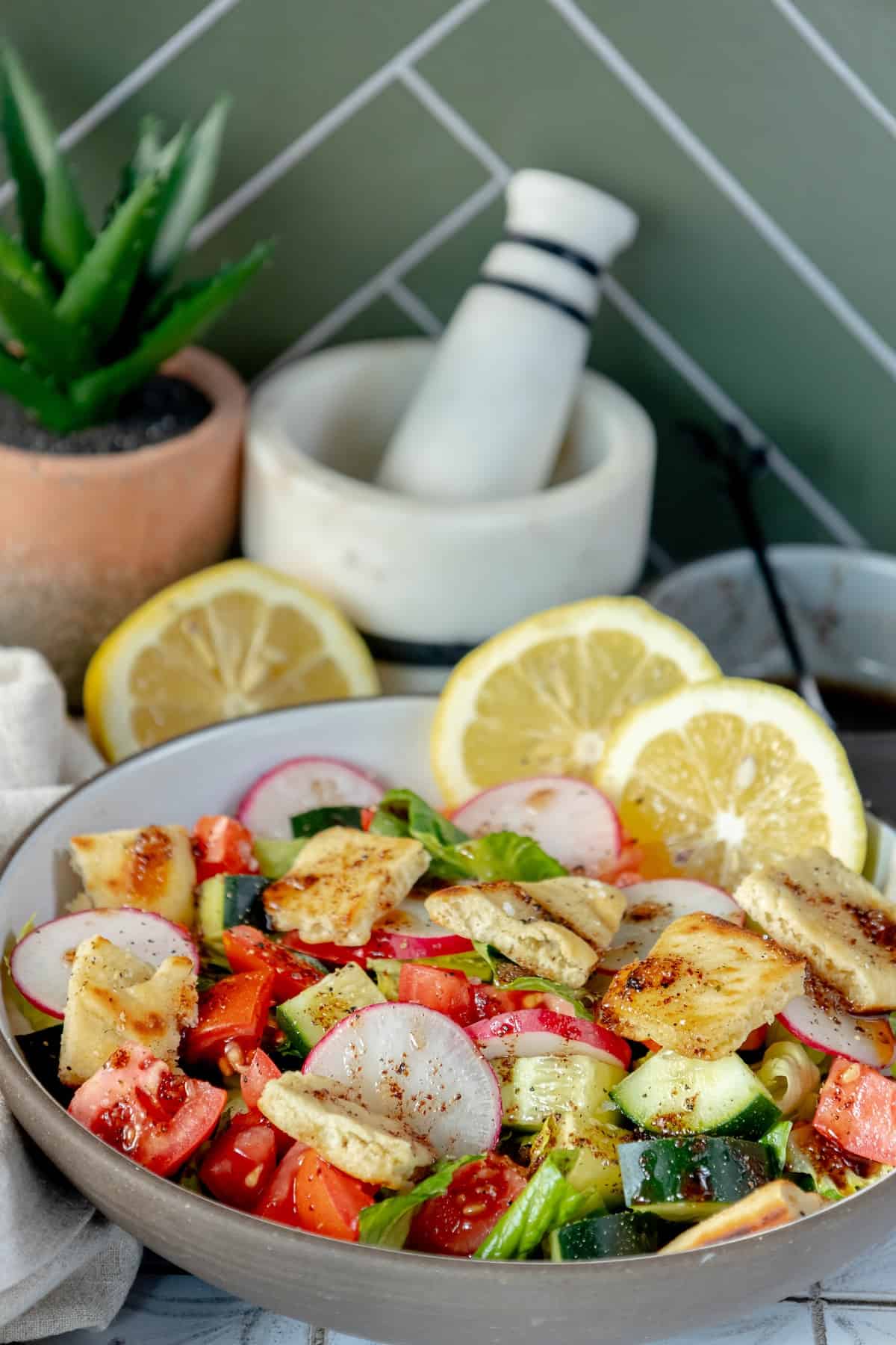 A Fattoush salad with lemons and a mortar.