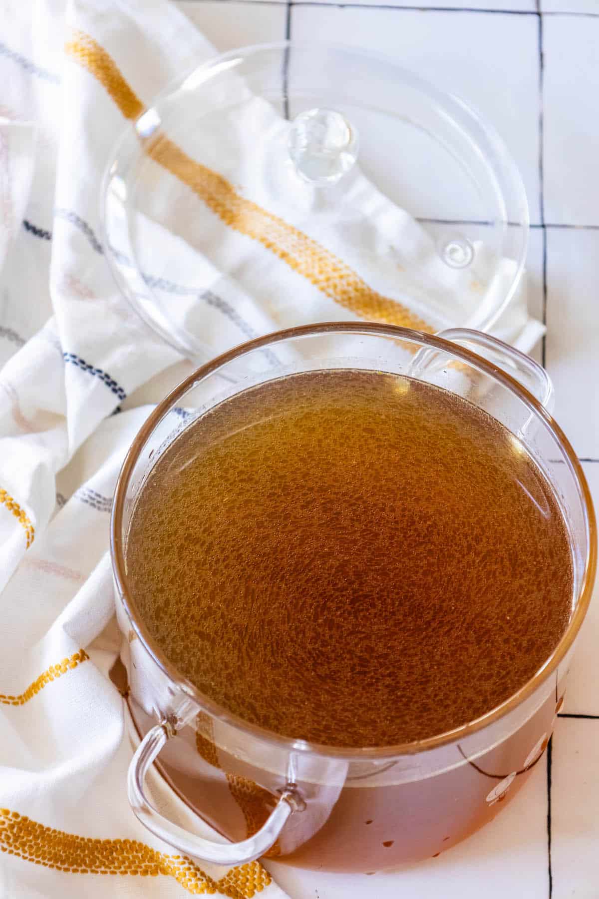 A bowl of brown gravy on a table with a towel.