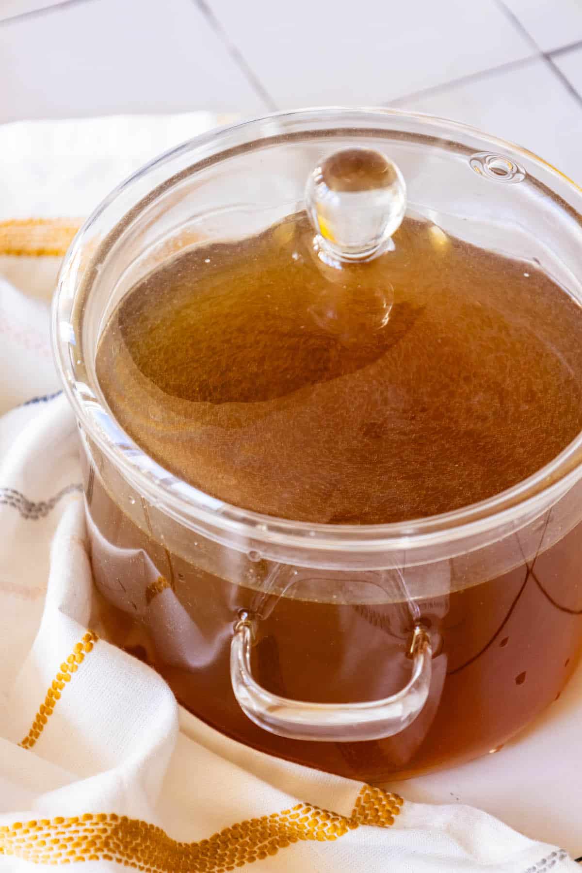 A glass pot with brown liquid on top of a white towel.