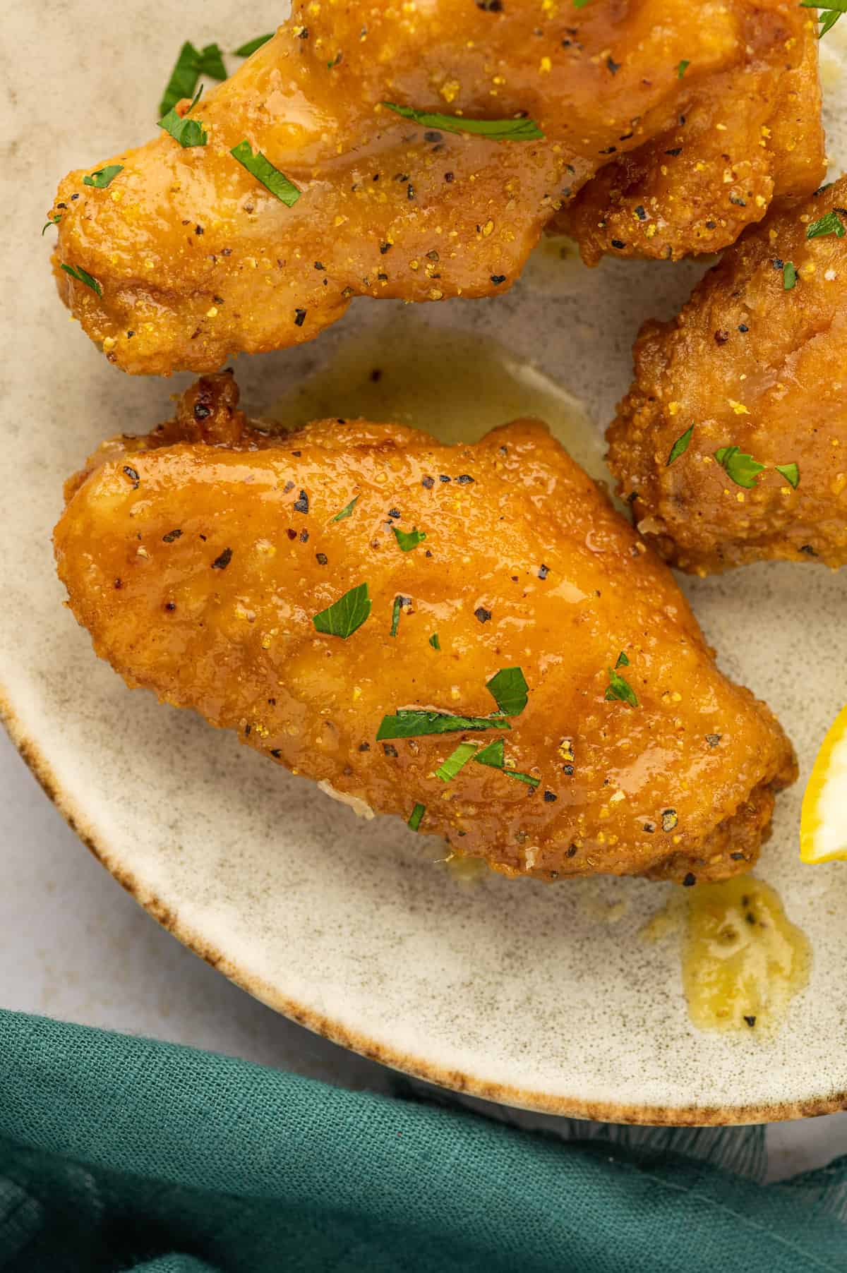 A plate of lemon pepper chicken wings with a lemon wedge on it.