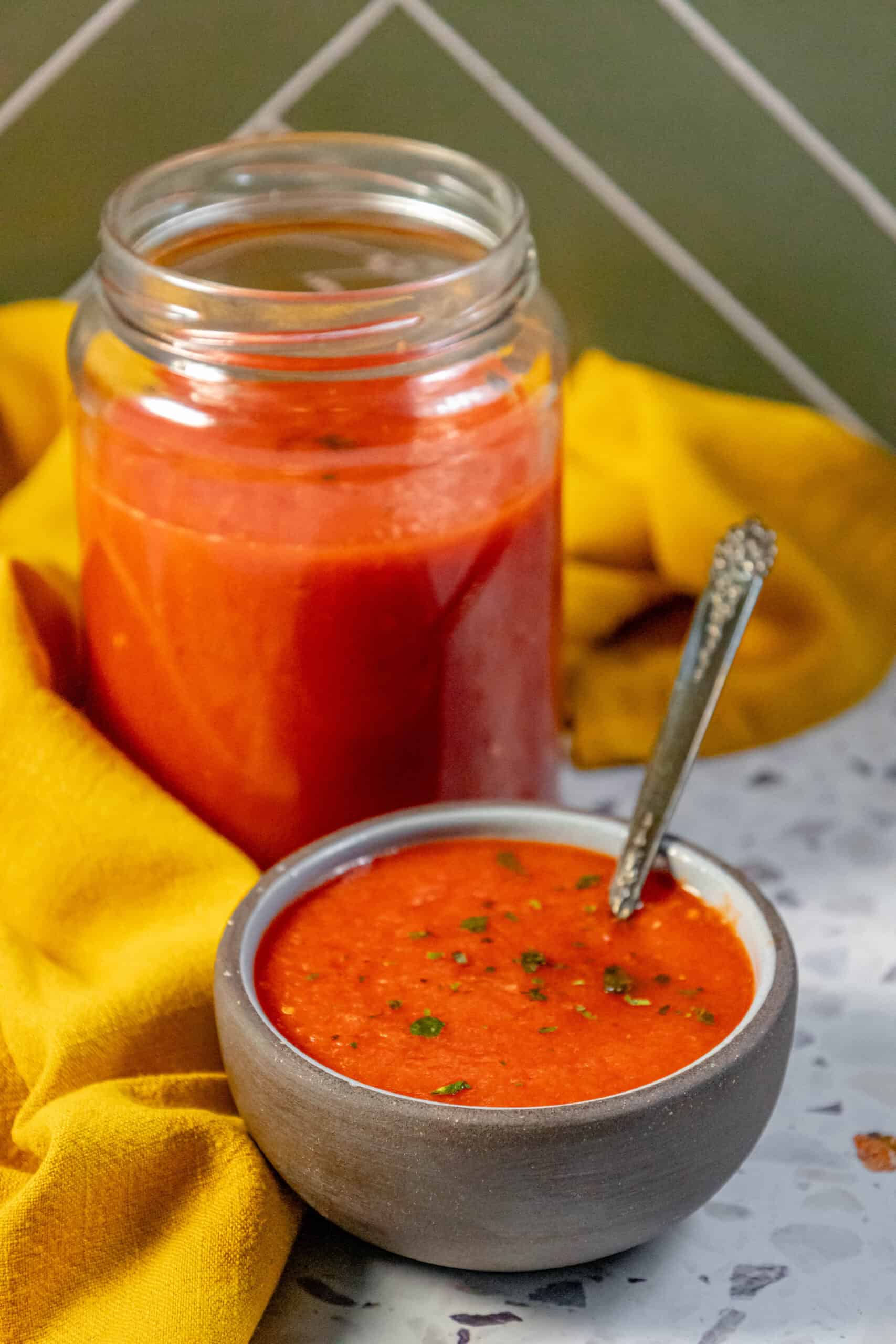 A jar of tomato soup with a spoon next to it, perfect for a comforting meal.