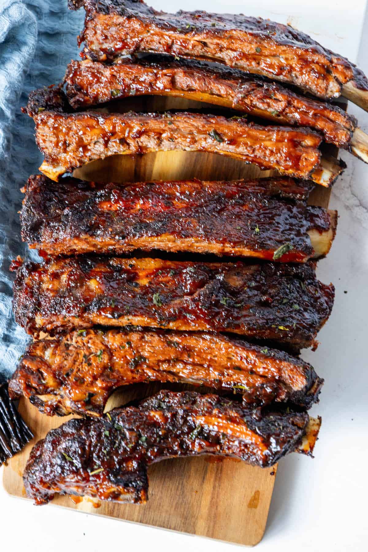 Oven-baked beef ribs on a wooden cutting board.