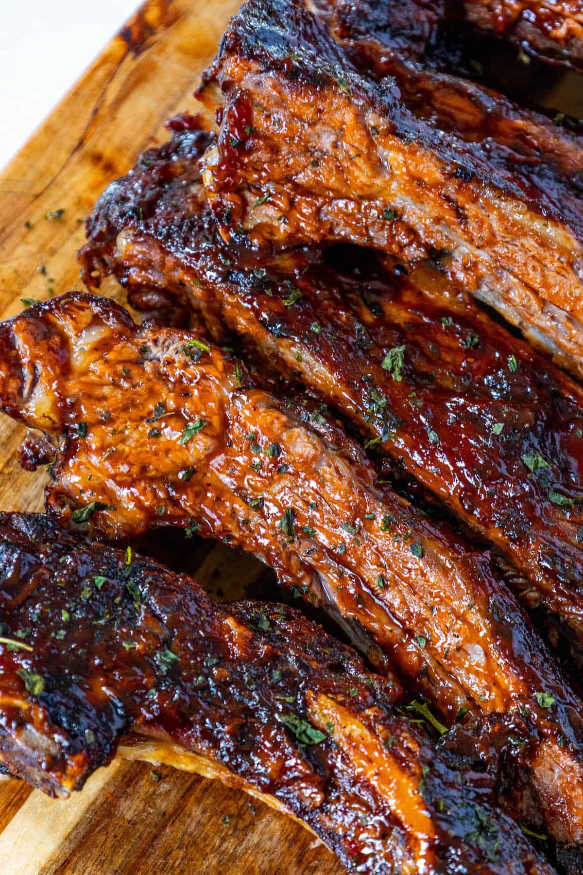 Oven baked beef ribs on a wooden cutting board.