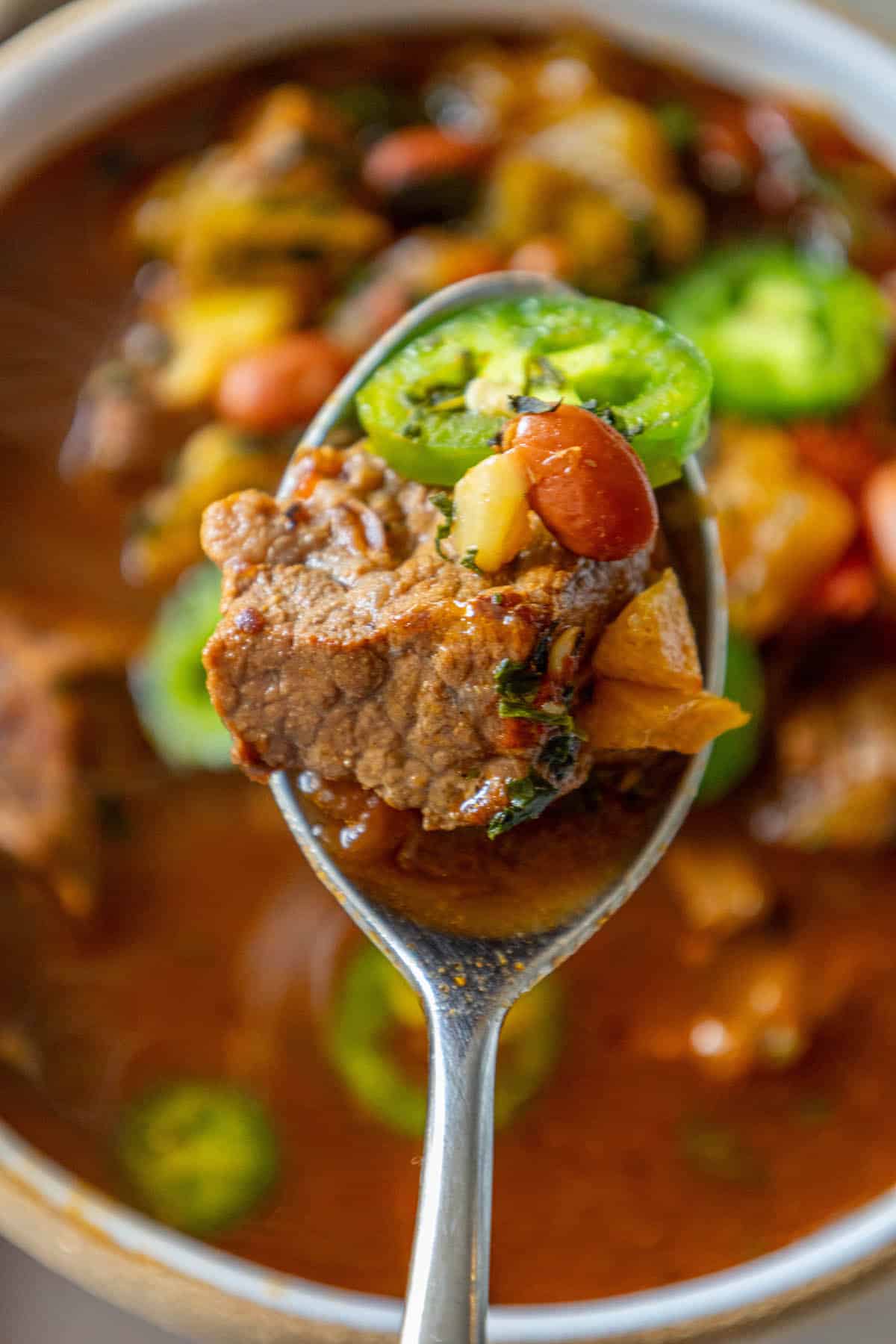 A spicy spoonful of beef soup with meat and beans in a bowl.