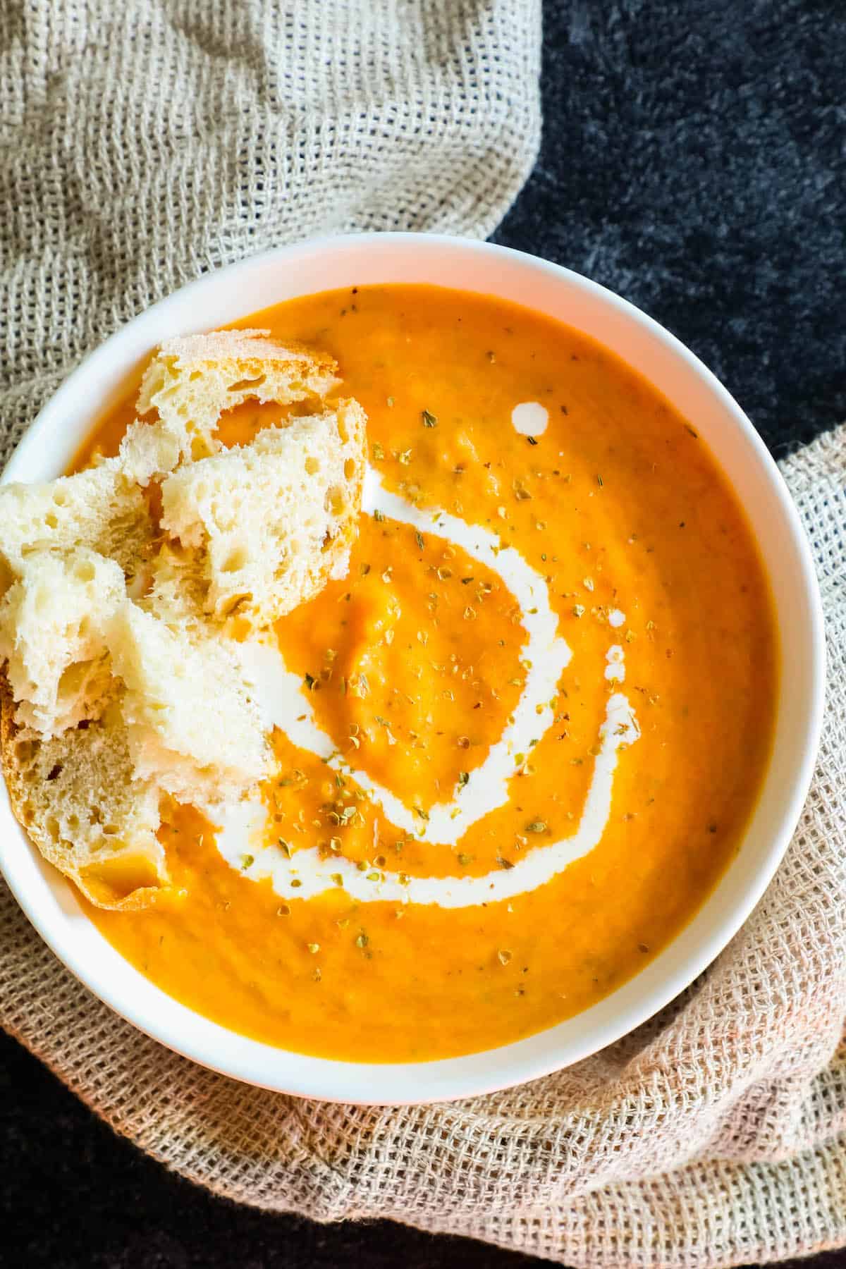 A bowl of carrot soup with croutons and sour cream.