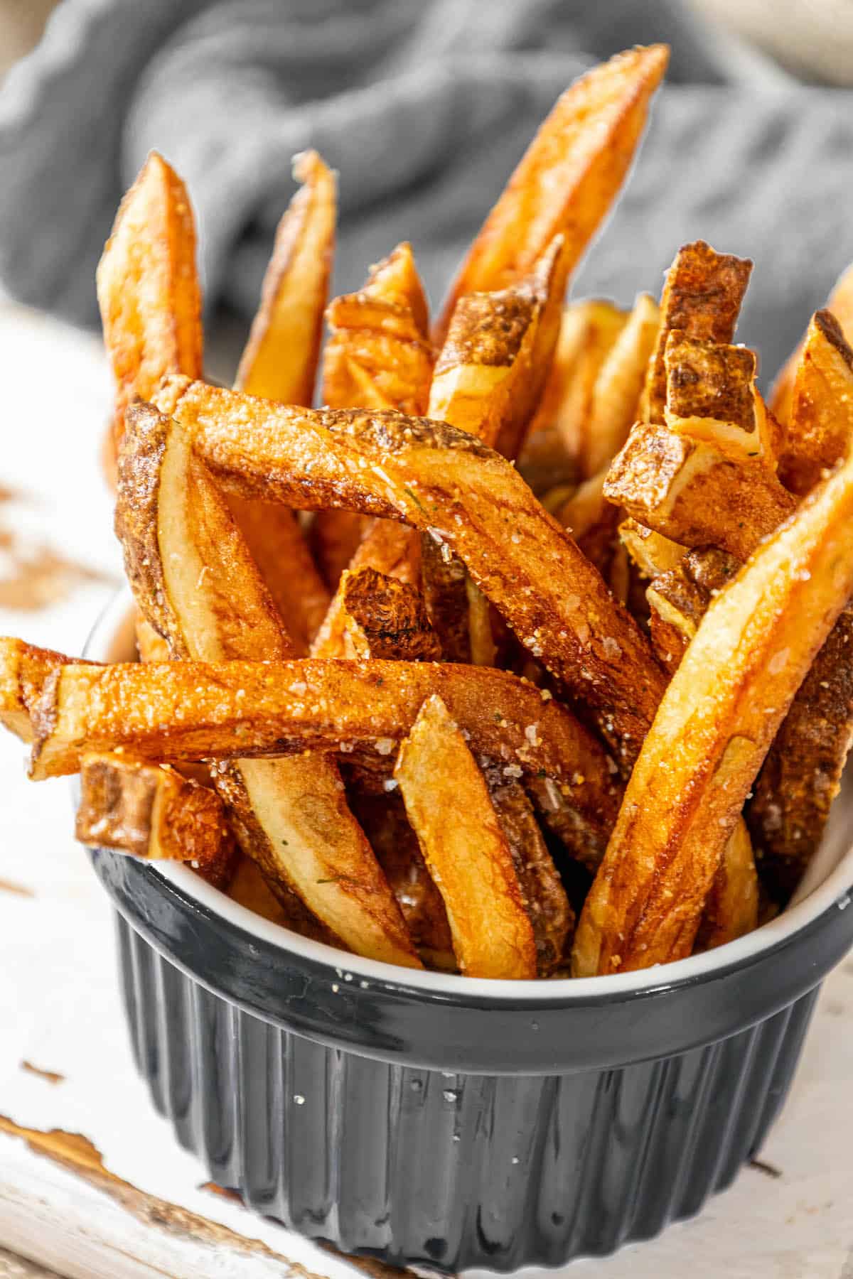 Crispy air fried sweet potato fries in a bowl on a wooden table.