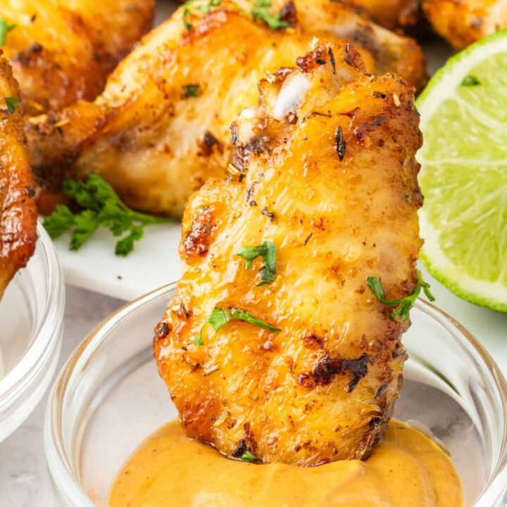 Crispy air fryer chicken wings served with tangy sauce and refreshing lime wedges.