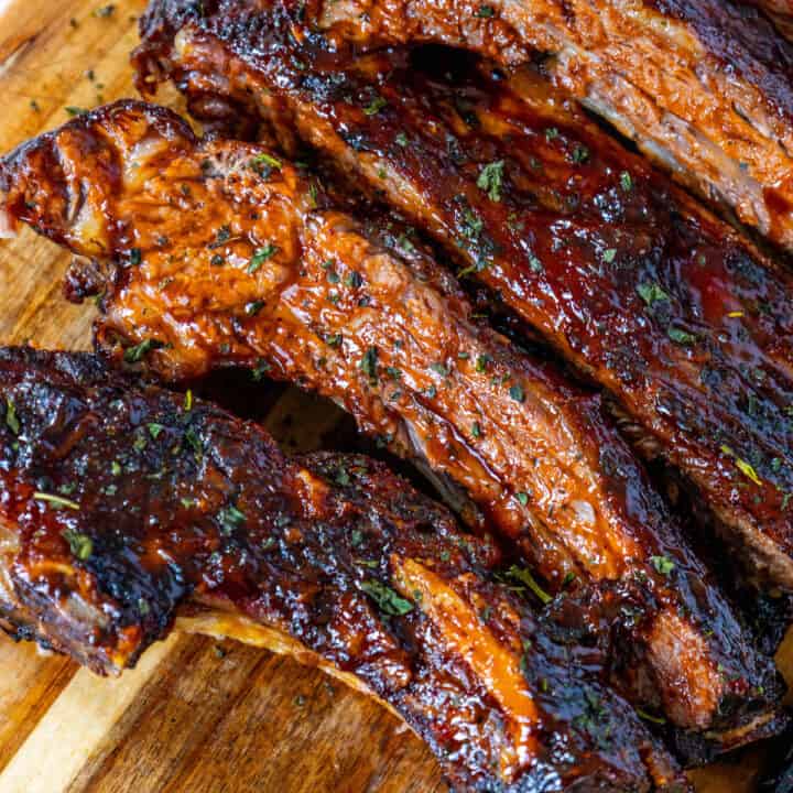 Oven-baked beef ribs on a wooden cutting board.