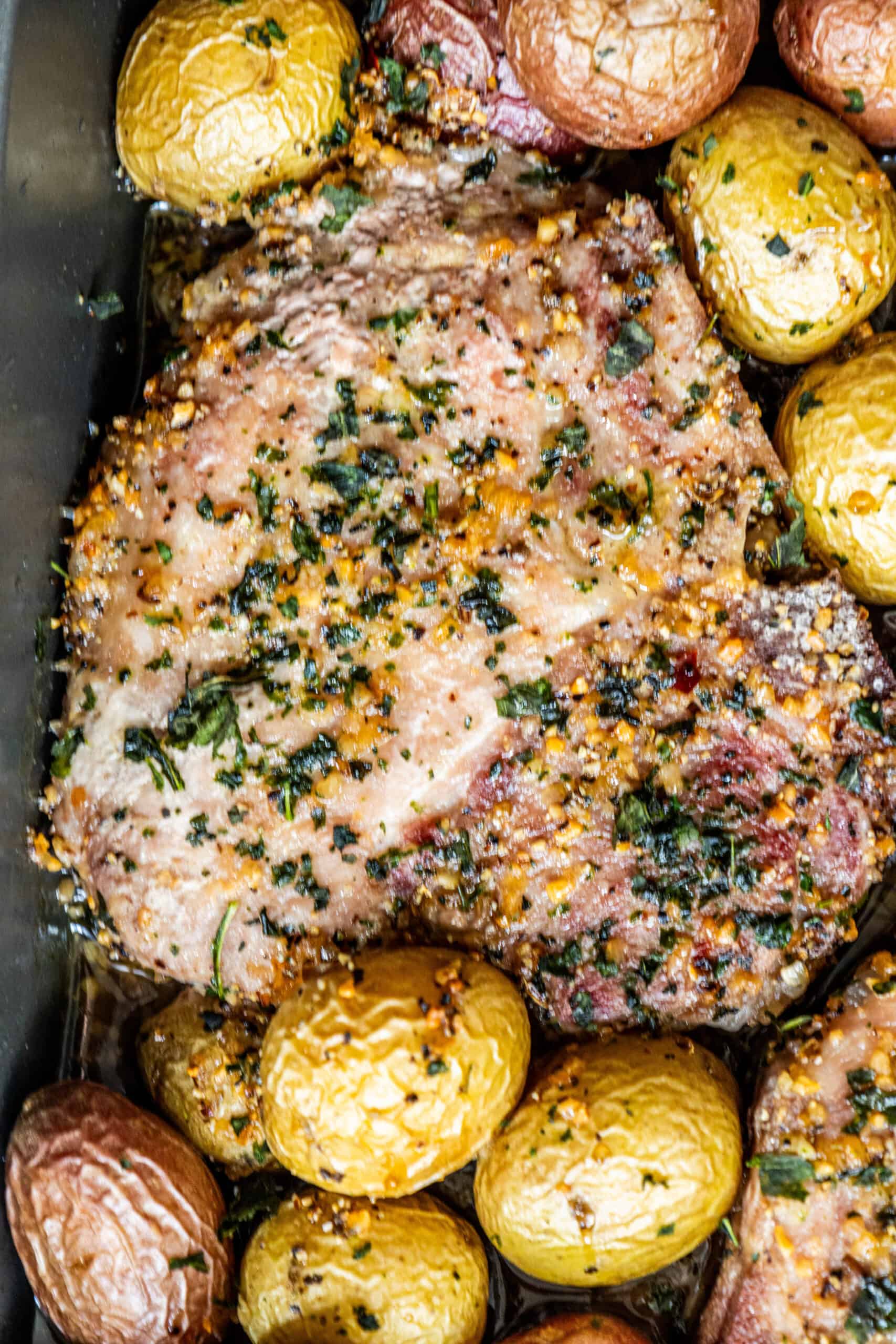 Pork chops with potatoes and herbs cooked in a baking dish.