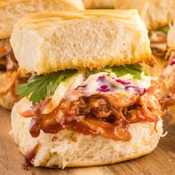 BBQ pulled pork sliders on a wooden cutting board.