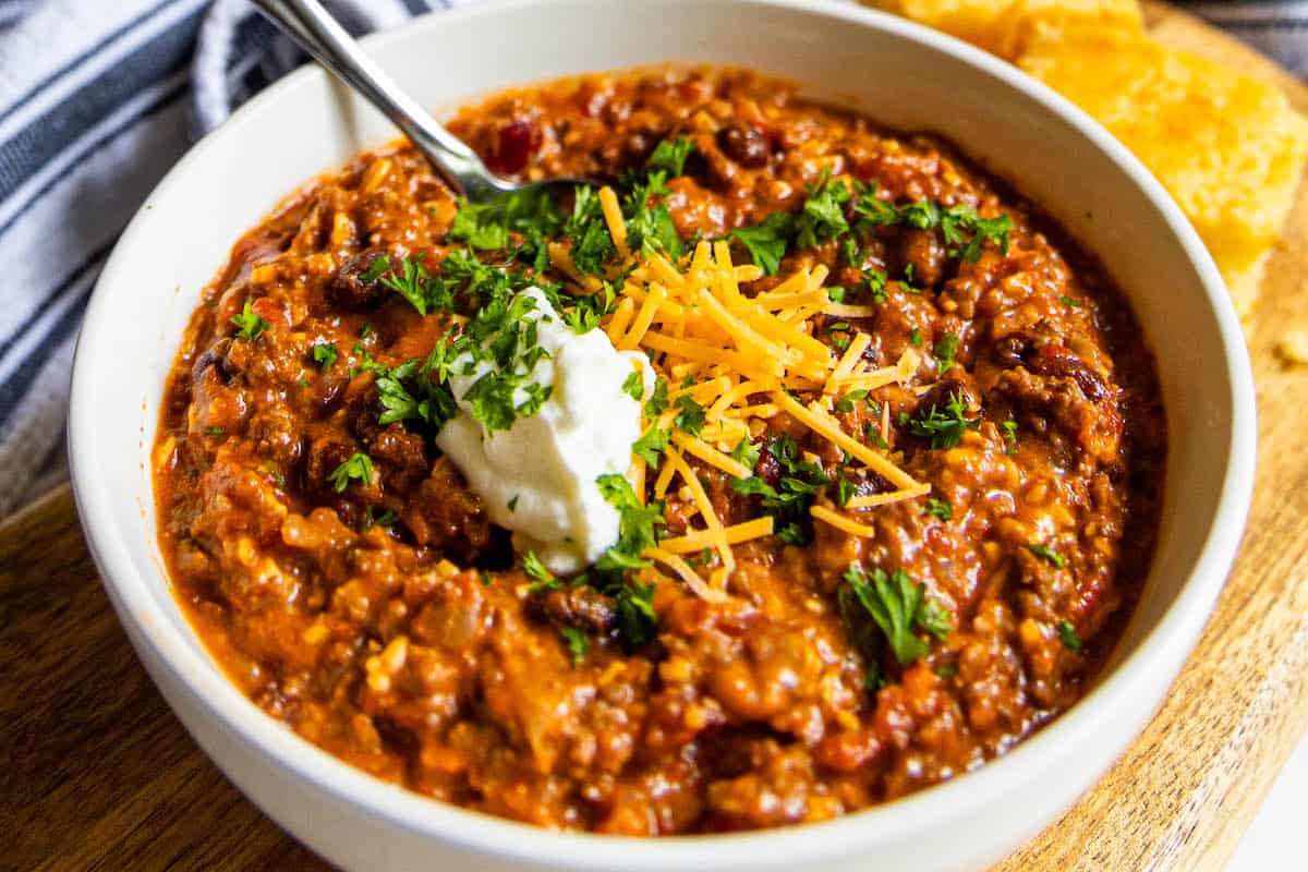 A bowl of chili with cheese and sour cream.