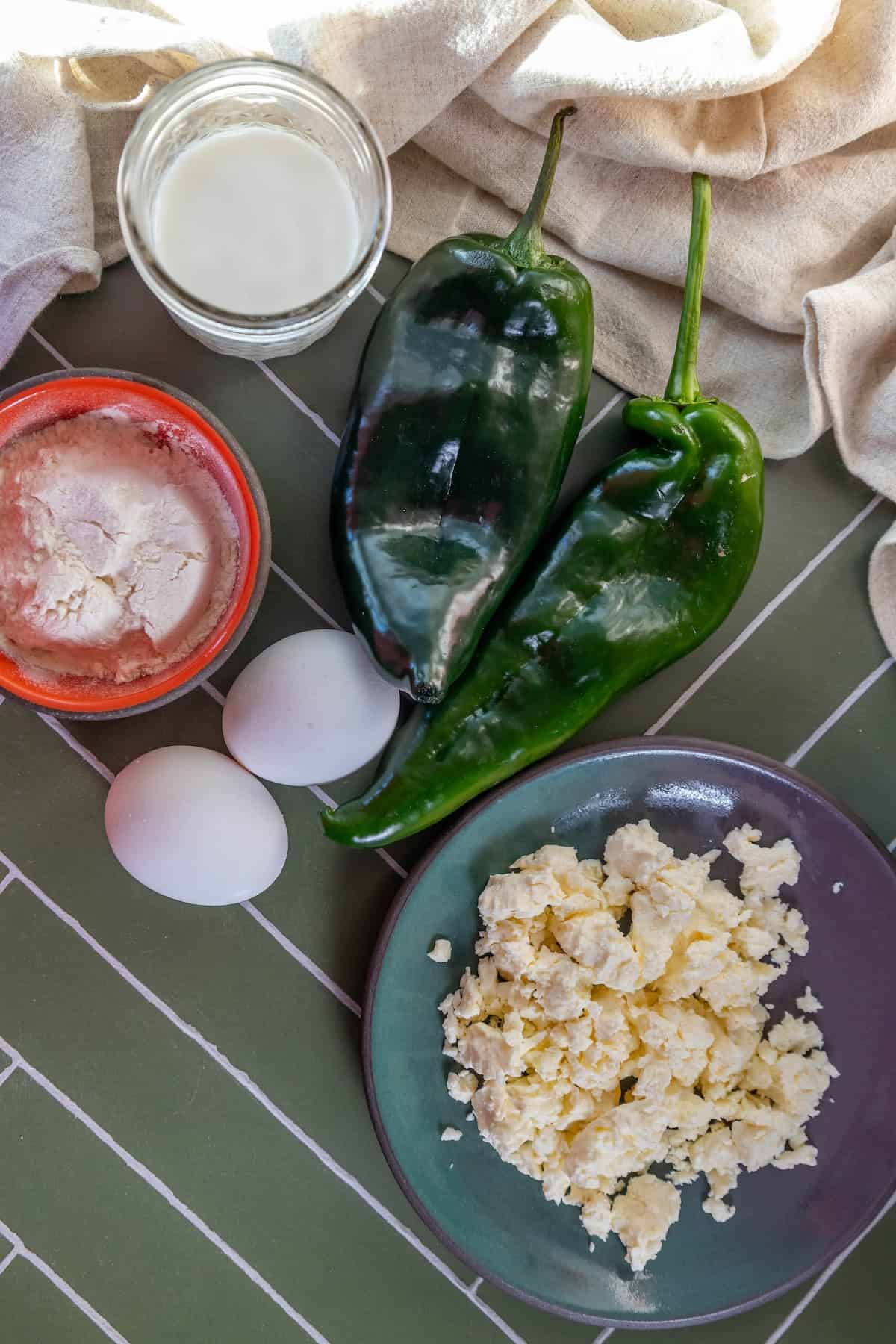 Ingredients for a Mexican omelet with jalapeños and eggs on a skillet.
