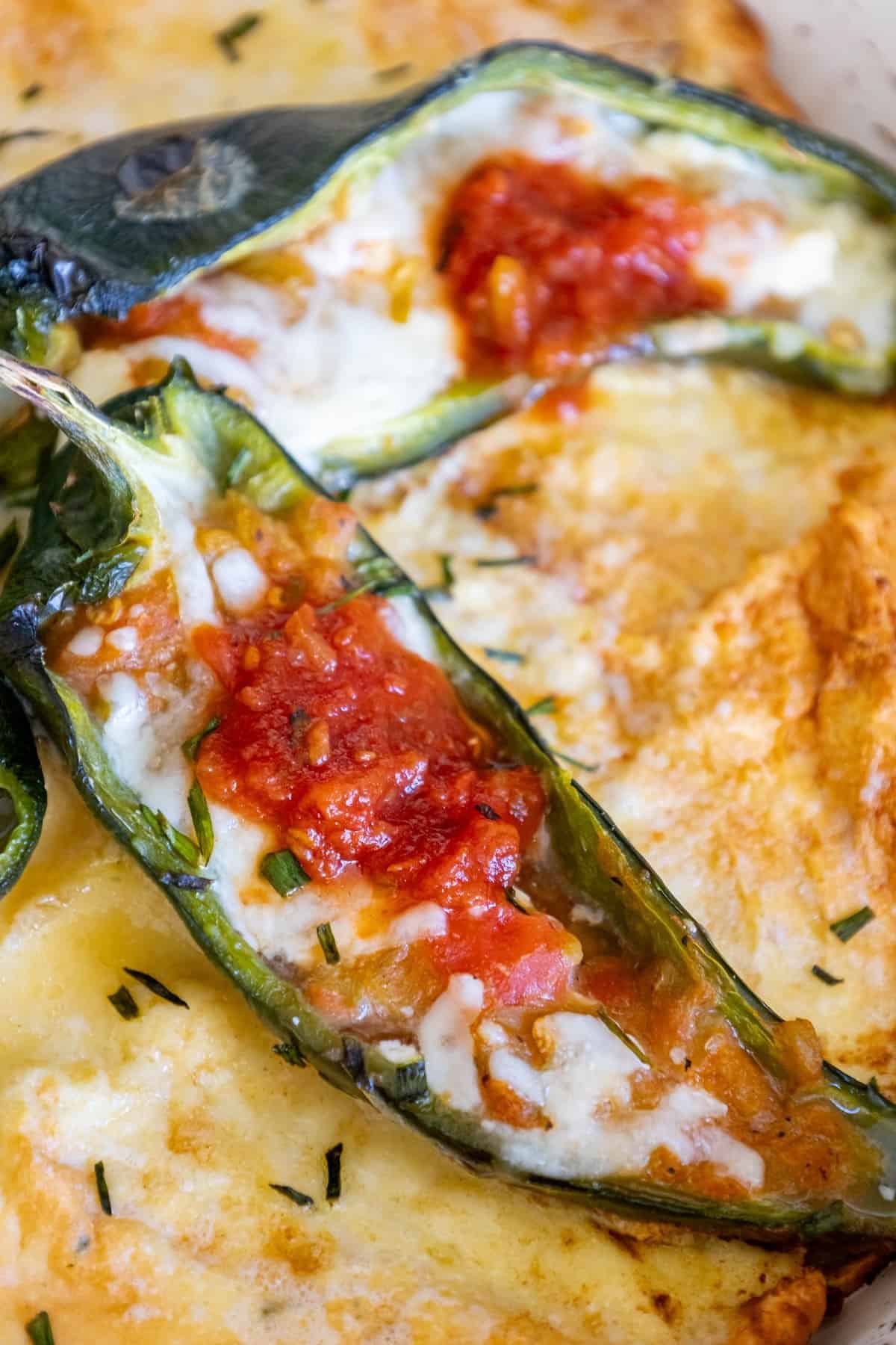 A skillet of stuffed jalapenos with cheese and sauce, similar to Chile Rellenos.