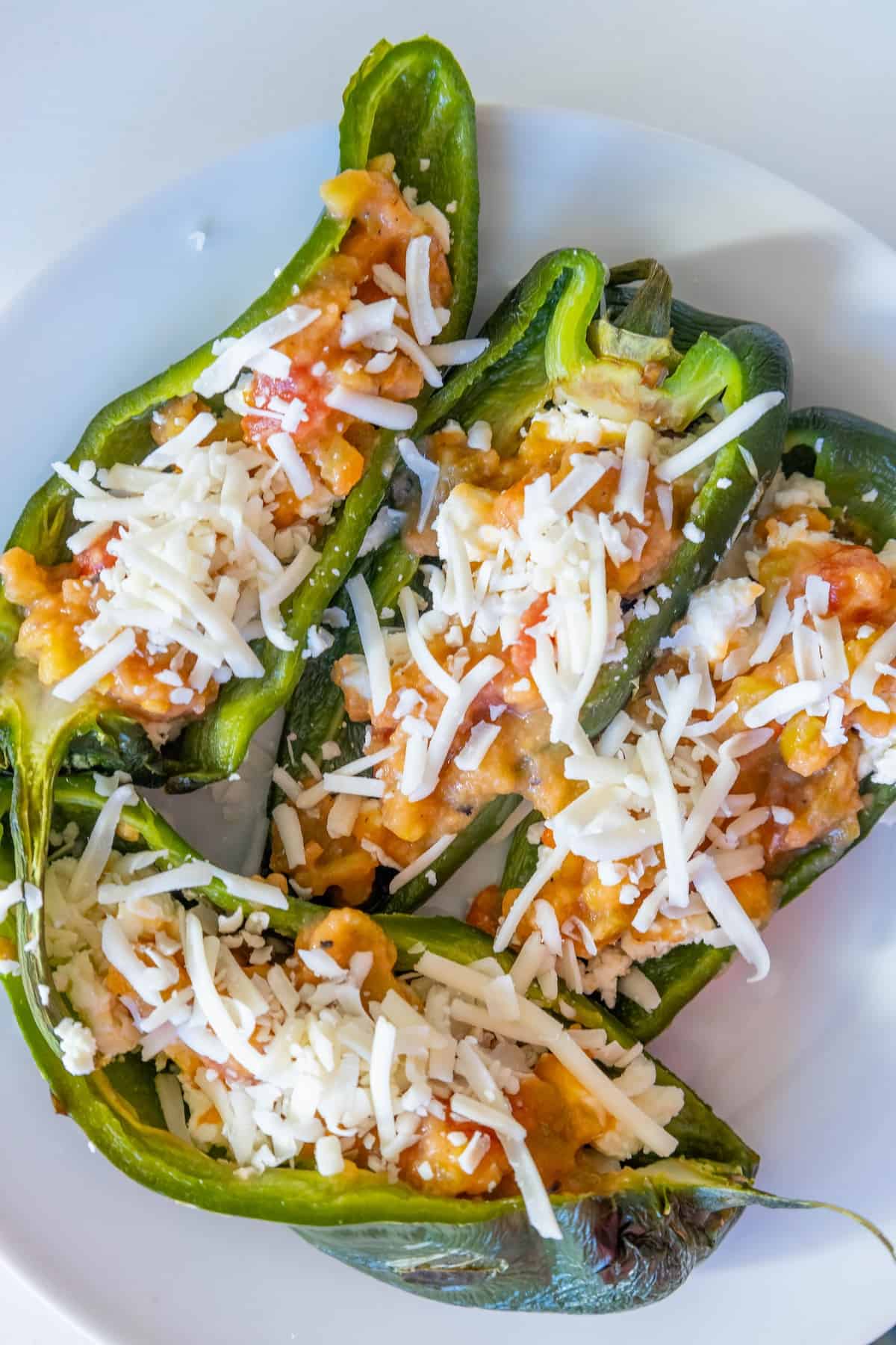 Stuffed jalapenos on a skillet with cheese and tomatoes.