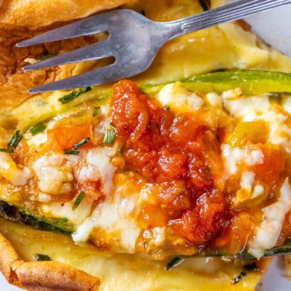 Zucchini quiche with cheese and tomato on a white plate.