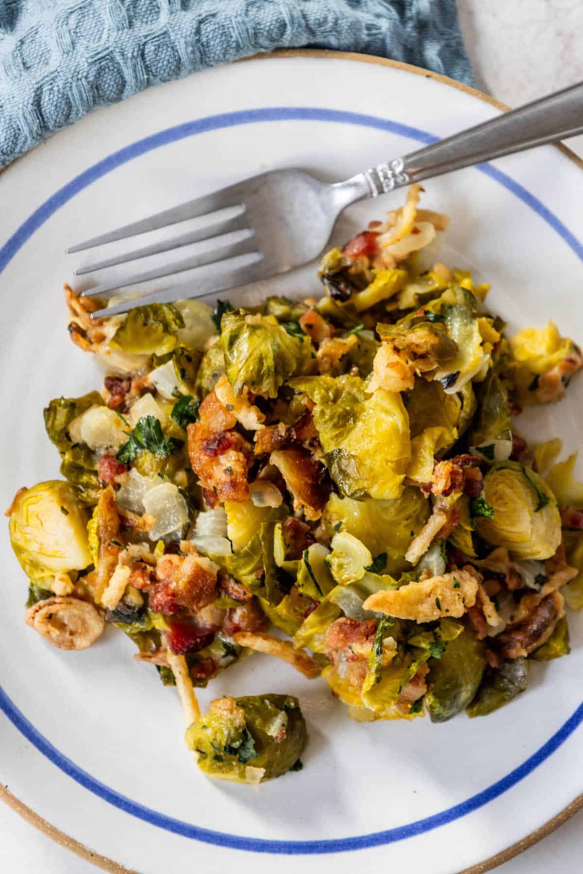 Creamy Brussels sprouts and bacon on a plate with a fork.