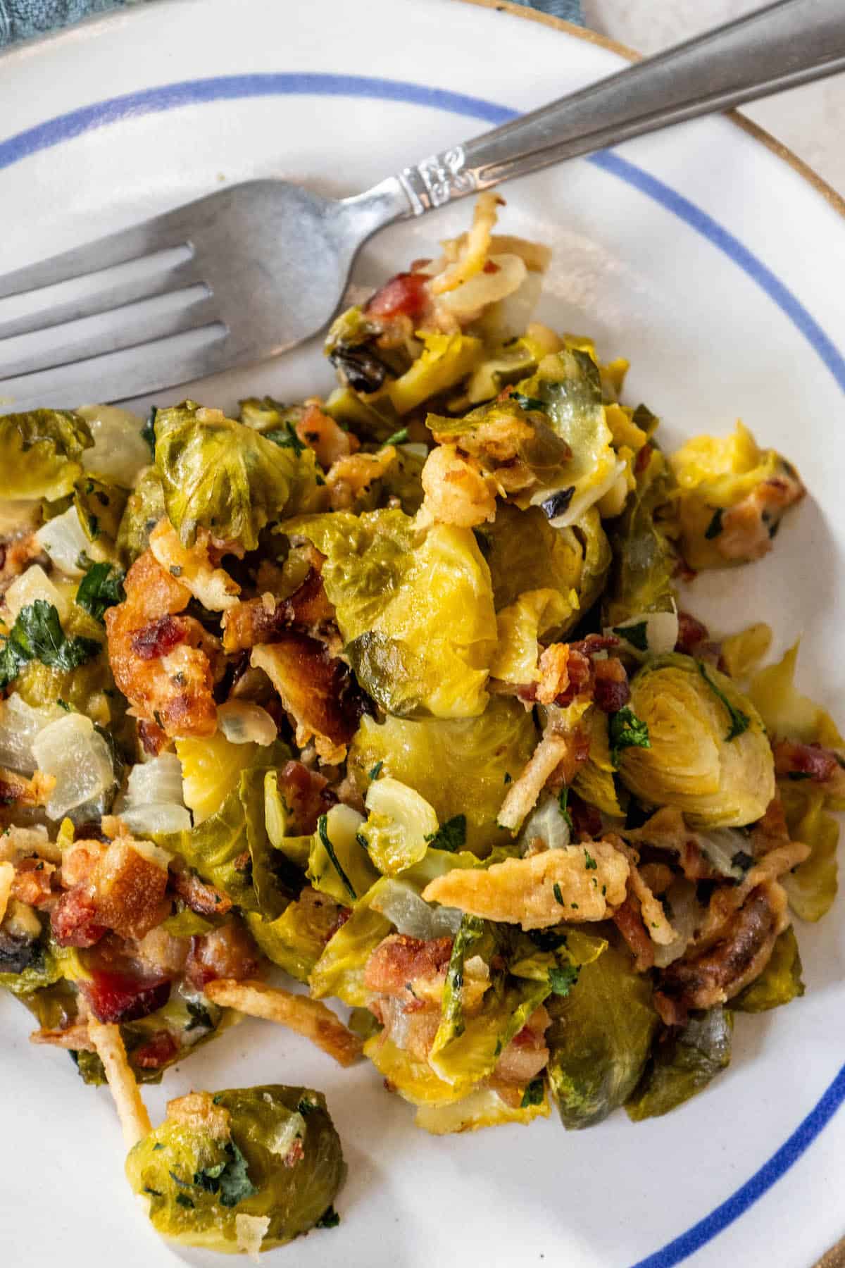 Brussels sprouts and bacon on a plate with a fork, creating a creamy and savory delight.