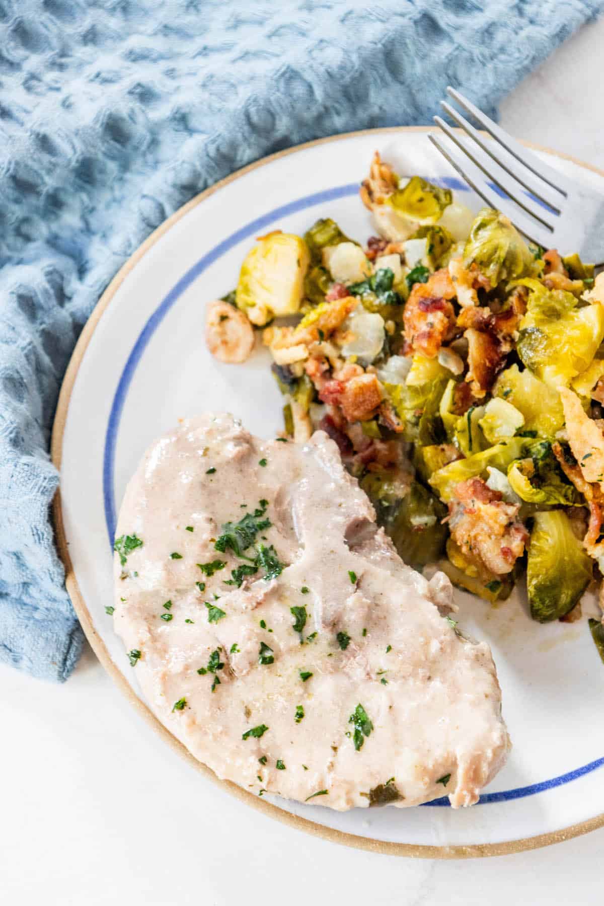 A creamy plate with chicken and brussels sprouts on it.