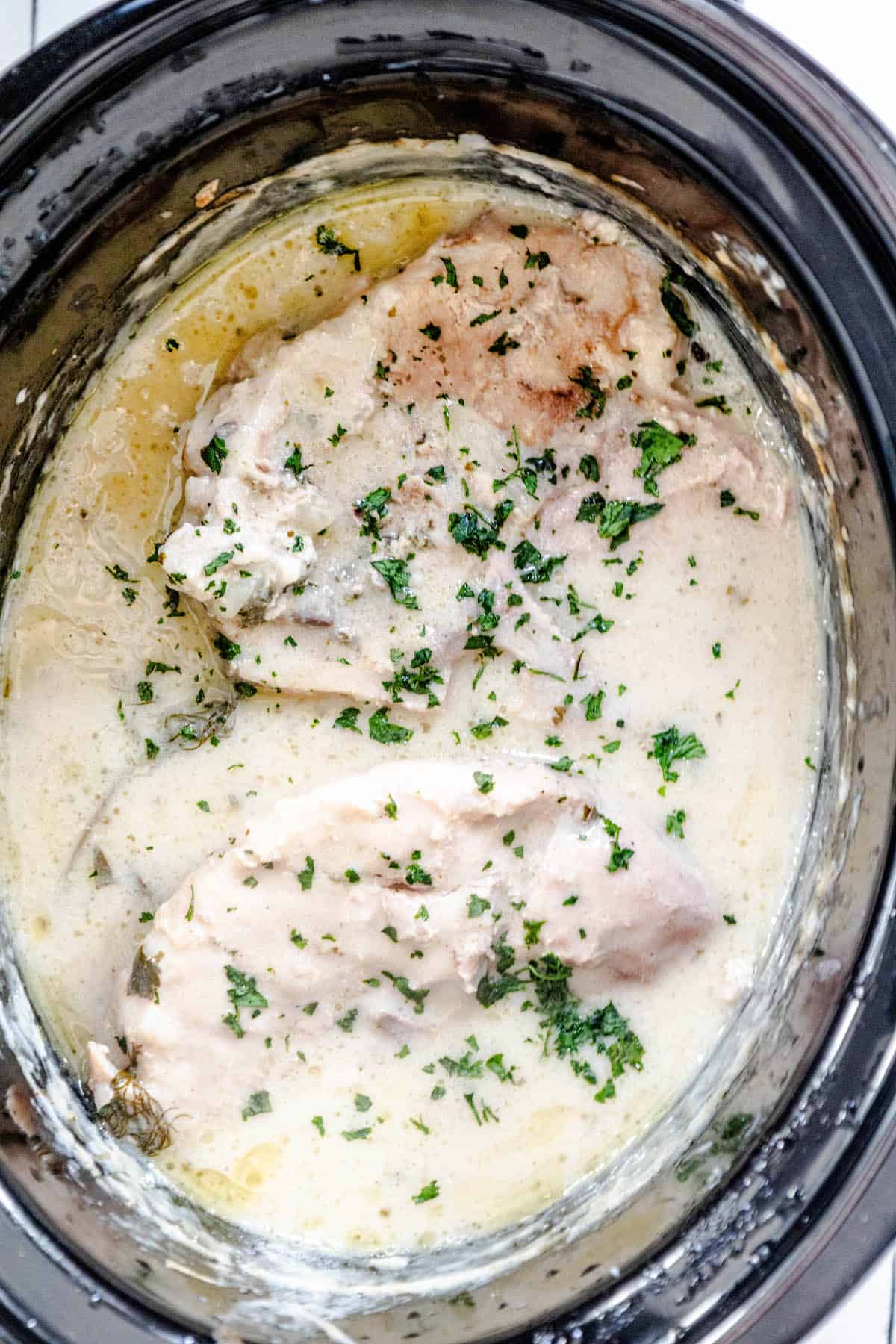 A crock pot filled with creamy chicken and gravy.