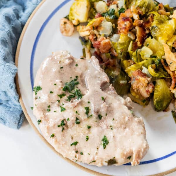 Creamy pork chops and brussels sprouts on a plate.