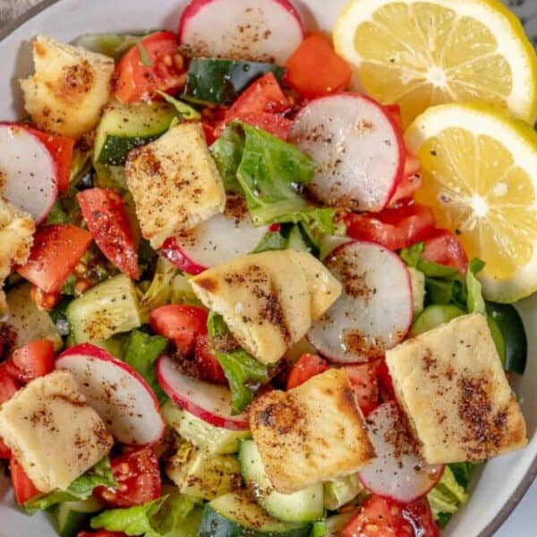 A bowl of salad with tomatoes, cucumbers and tofu.
