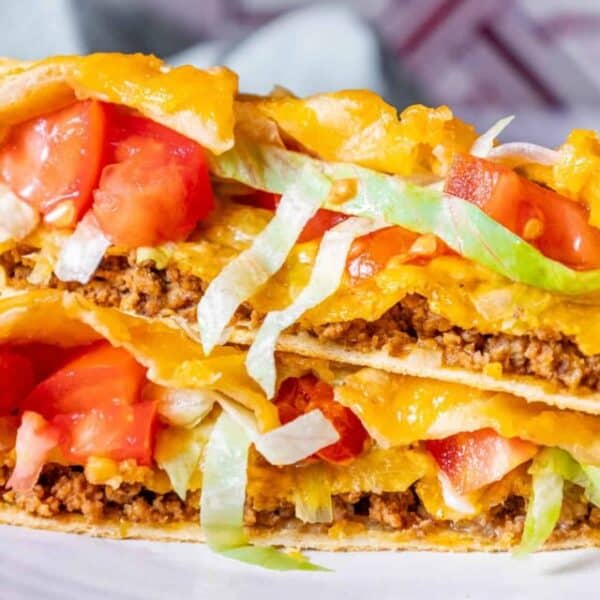 A stack of tacos on a plate with tomatoes and lettuce.