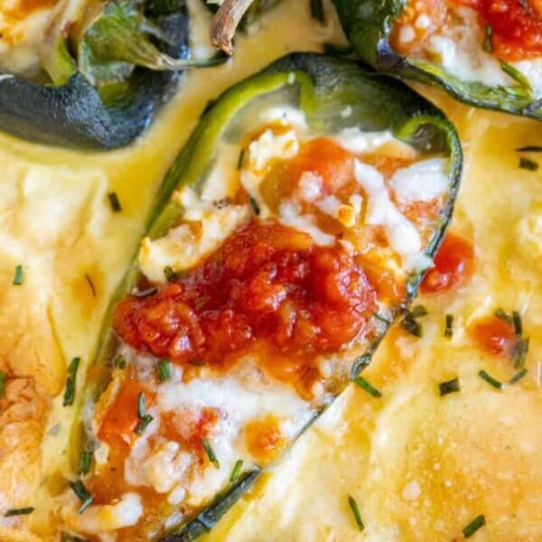 Stuffed jalapenos in a dish with cheese and tomatoes.