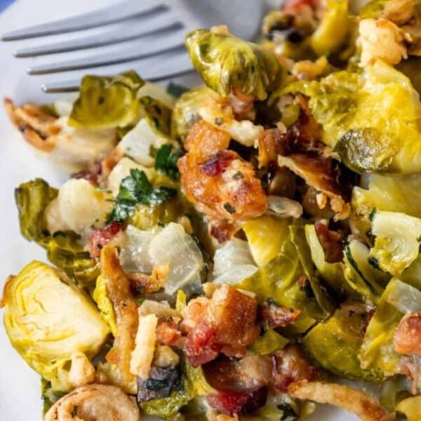 A plate of brussels sprouts and bacon with a fork.
