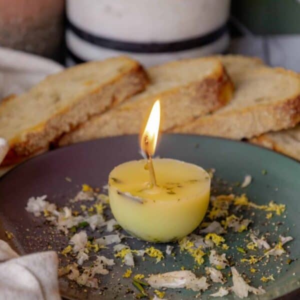 A candle is sitting on a plate next to some bread.