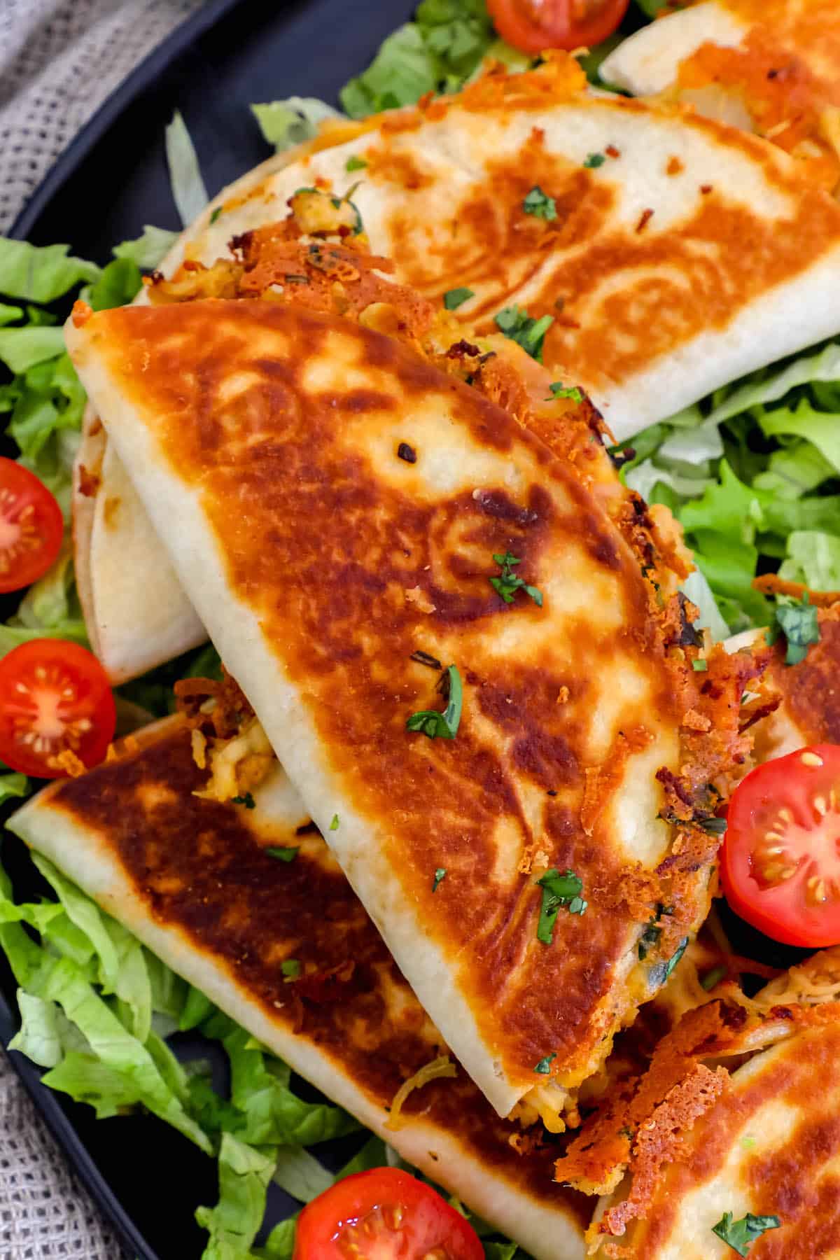 Mini chicken quesadillas on a plate with tomatoes and lettuce.