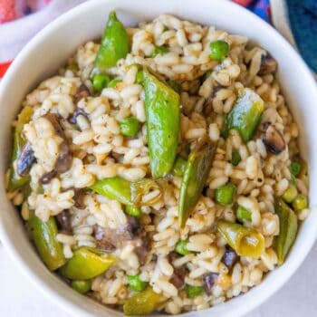 Risotto with mushrooms and peas in a white bowl.