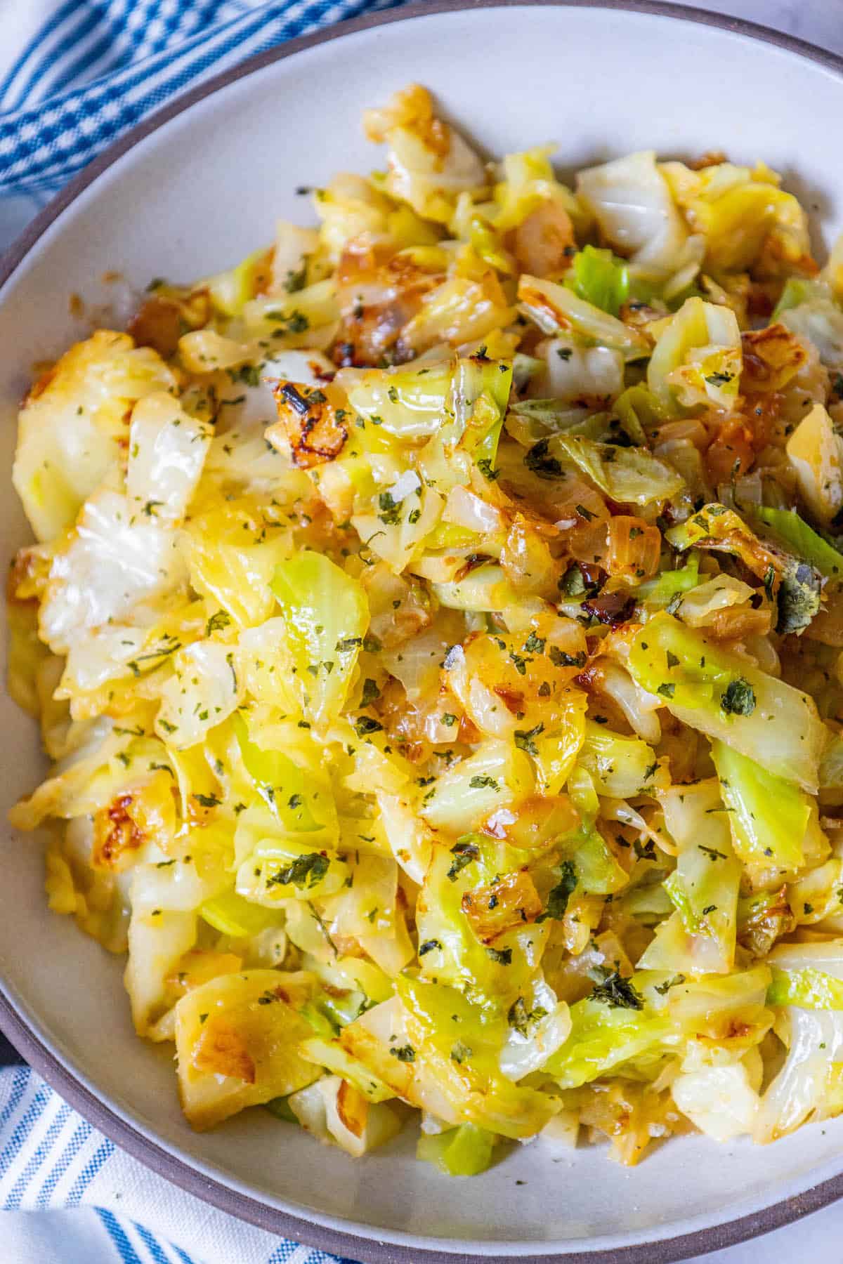 A bowl of fried keto cabbage on a blue and white cloth.