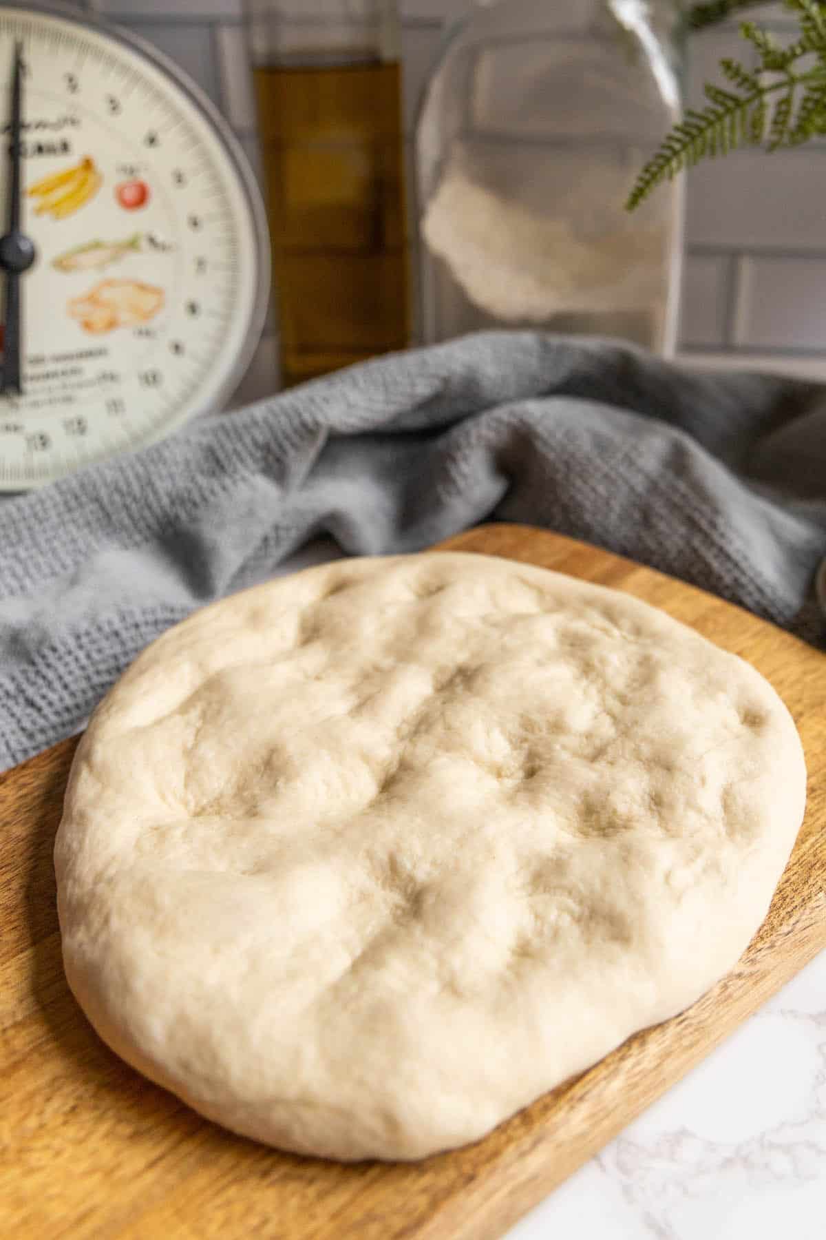 A wooden cutting board with a pizza dough on it.