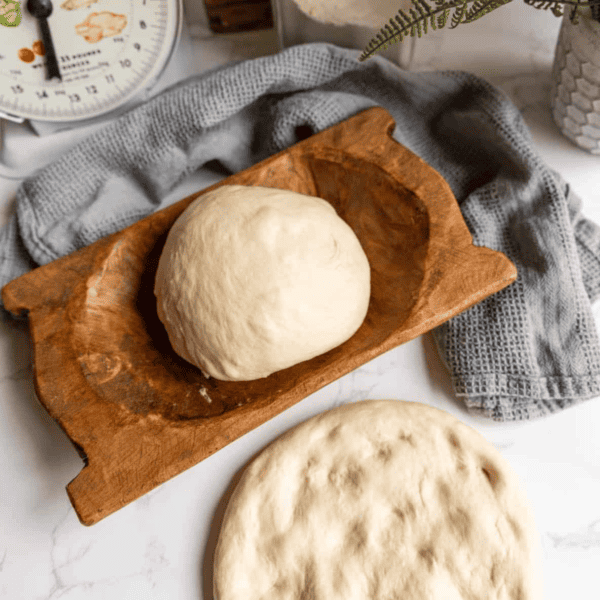 Homemade pizza dough on a wooden board.