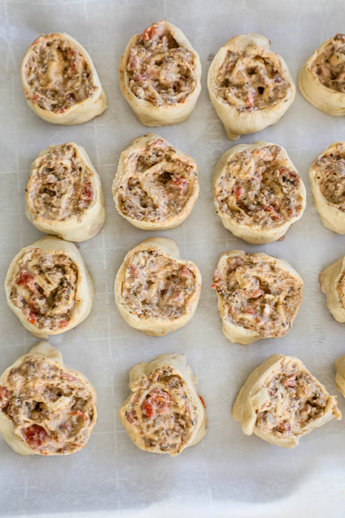 A baking sheet with a tray of mini pizzas on it.