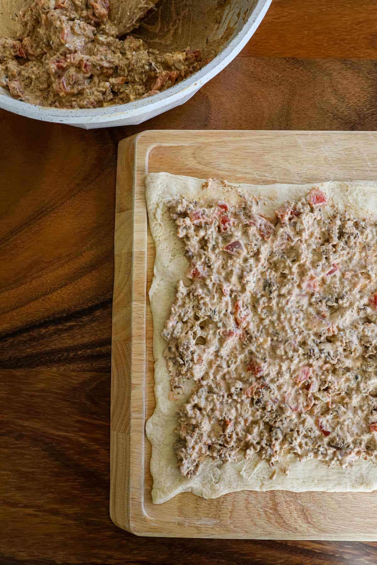 A dough on a cutting board next to a bowl of food.