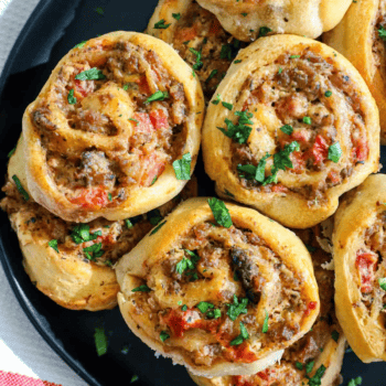 Sausage meatball rolls on a black plate.