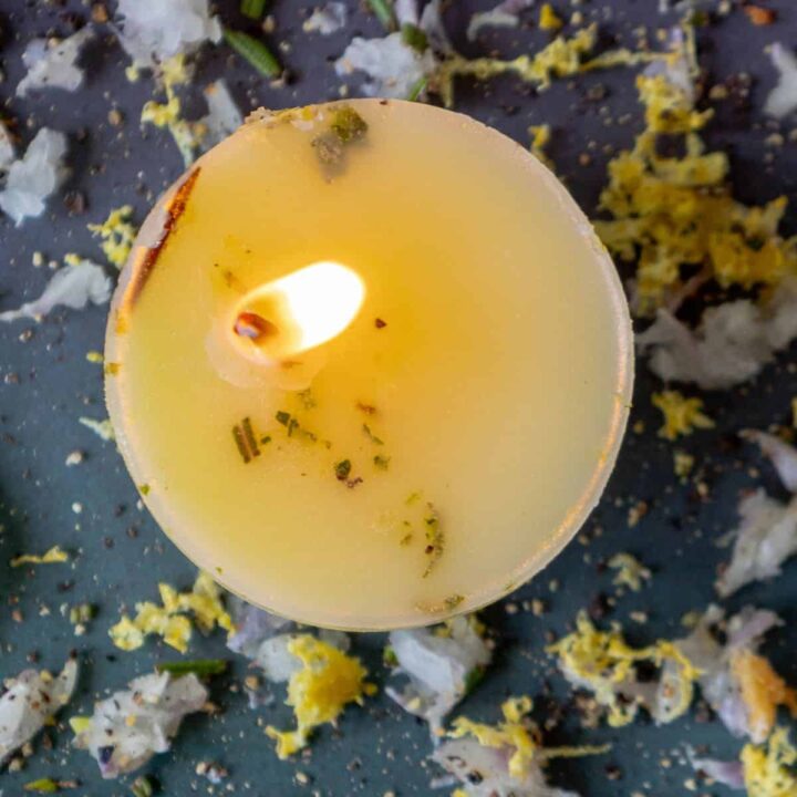 A tallow candle surrounded by flowers and leaves.