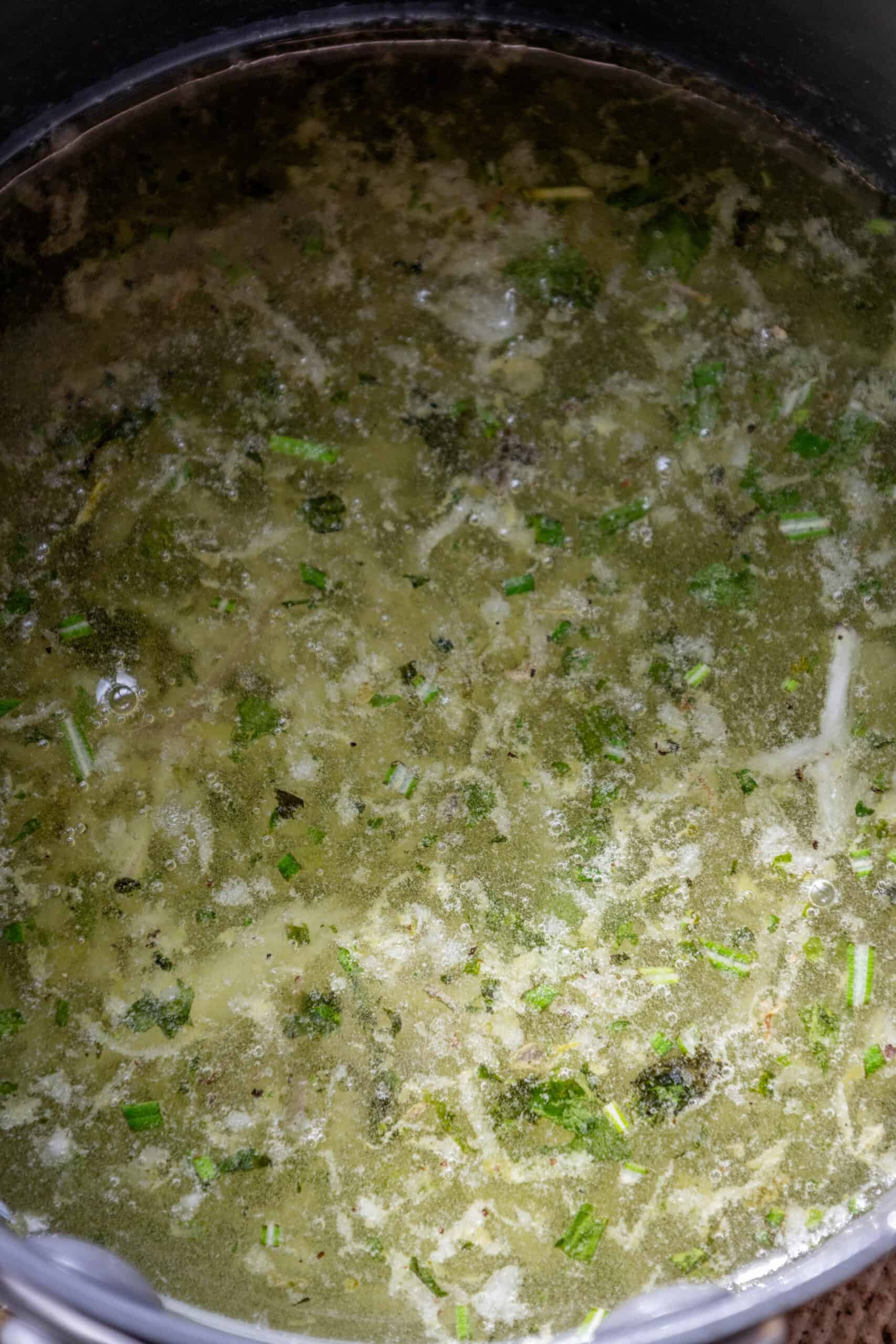 A pot of soup with broccoli and tallow candles in it.