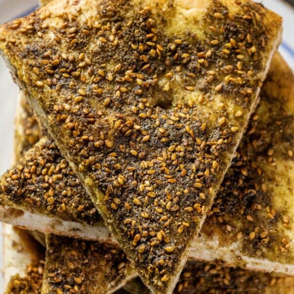 A plate with a piece of bread with sesame seeds and Za'atar on it.