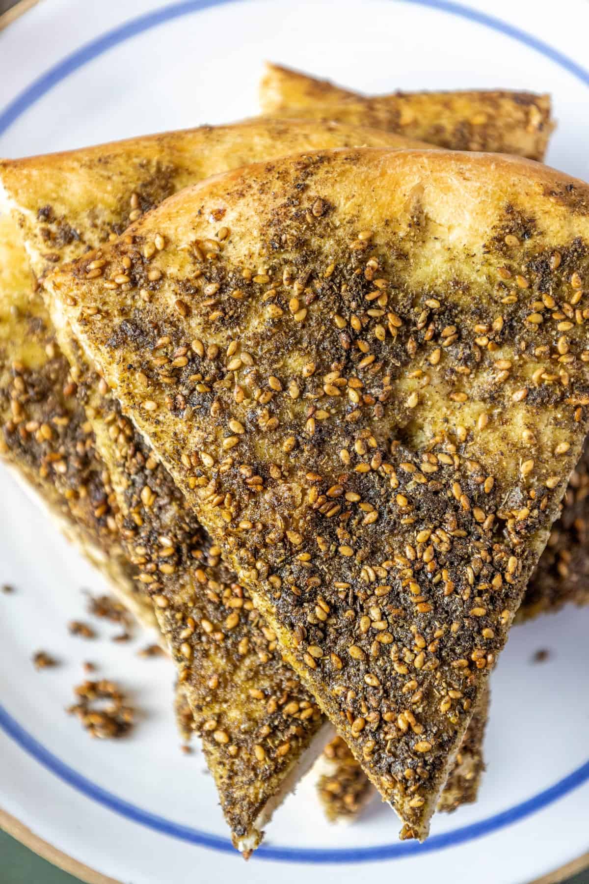 A plate of bread with sesame seeds on it, known as a za'atar manakish or za'atar pizza.